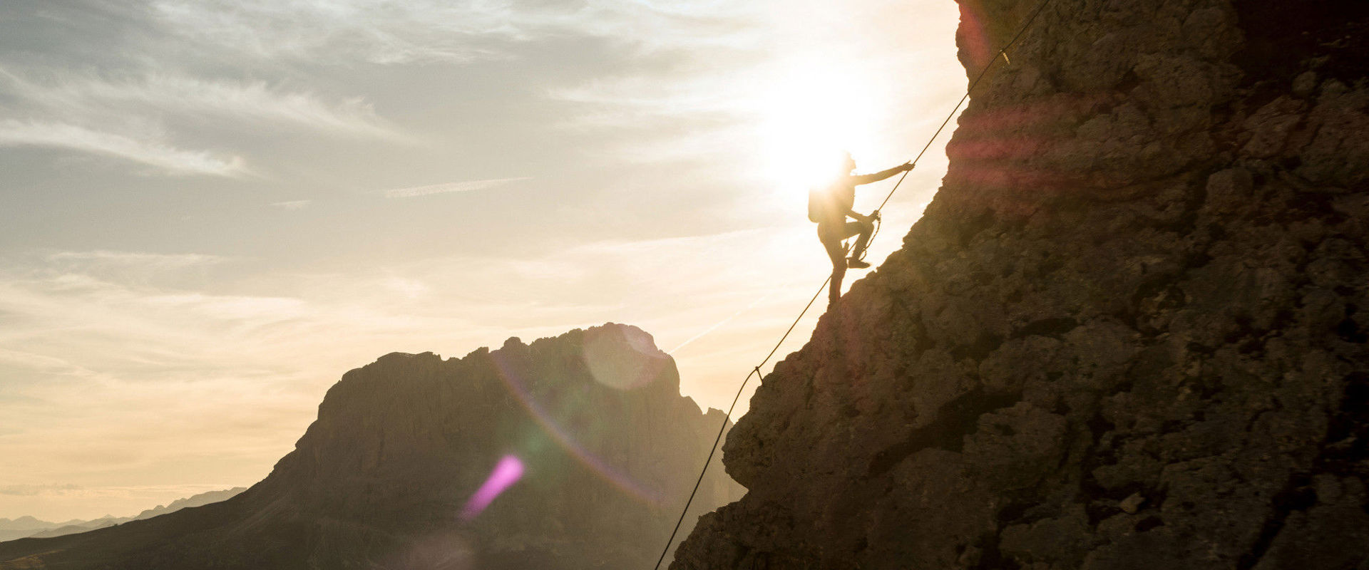 Via ferratas in the Dolomites A man holds on to the via ferrata rope and walks up the mountain.